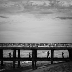 Silhouette people standing at beach against sky