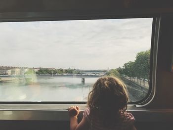 Rear view of girl looking through window