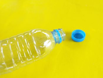 High angle view of bottle on glass against yellow background