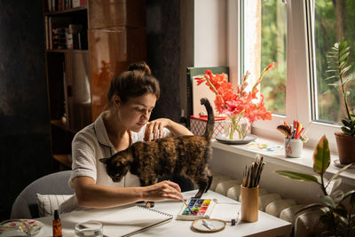 Female painter artist making an abstract watercolor painting. painting with cat