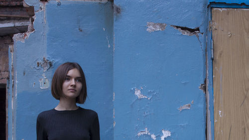 Close-up of young woman against blue door