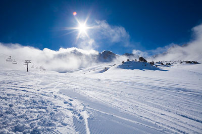 Scenic view of snow covered mountains against blue sky