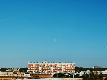 Buildings in city against clear blue sky