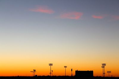 Low angle view of street lights against orange sky