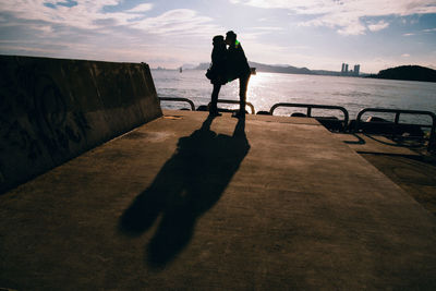 Shadow of man standing on sea shore against sky