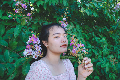 Portrait of beautiful young woman against pink flowering plants