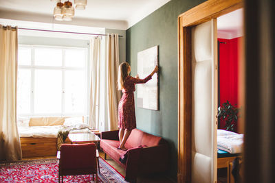 Woman decorating wall at home