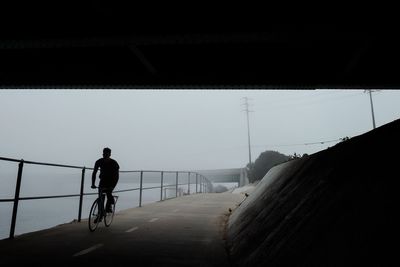 Man riding bicycle on road against clear sky