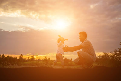 People standing on field against sky during sunset