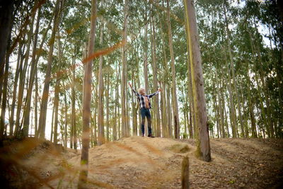 Man standing by trees in forest