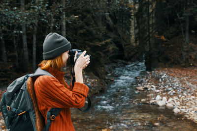 Rear view of woman photographing in forest