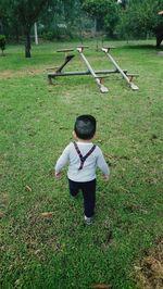 Rear view of boy walking towards seesaw at park