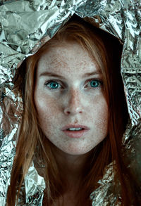 Close-up portrait of young woman with freckles on face