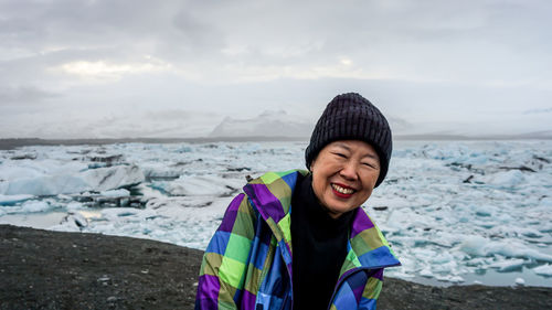 Smiling young woman against sky during winter