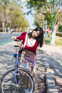 Woman with bicycle standing on road