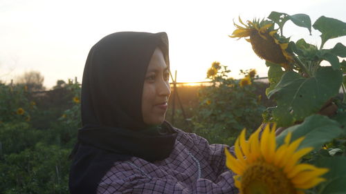 Woman standing by sunflower against sky