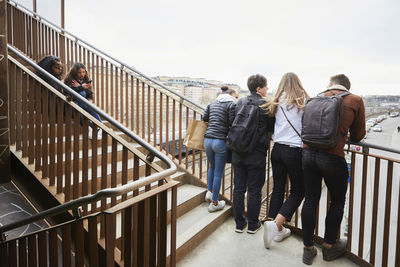 Teenage male and female friends on staircase in city