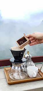 Hand holding coffee cup and table against clear sky