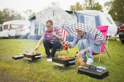 Men barbecuing in rain