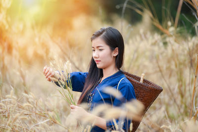 Young woman wearing traditional clothing while carrying basket amidst crops at farm