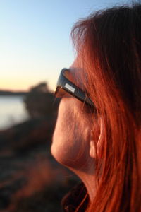 Close-up portrait of woman using smart phone against sky