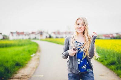 Portrait of smiling young woman standing on field