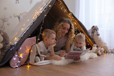 Mother reading stories while lying down in tent at home