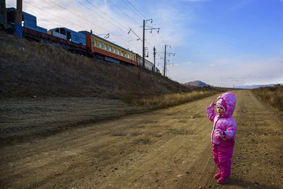 Full length of girl standing on road against sky