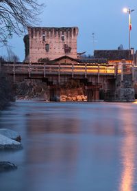 Bridge over river in city against sky during winter