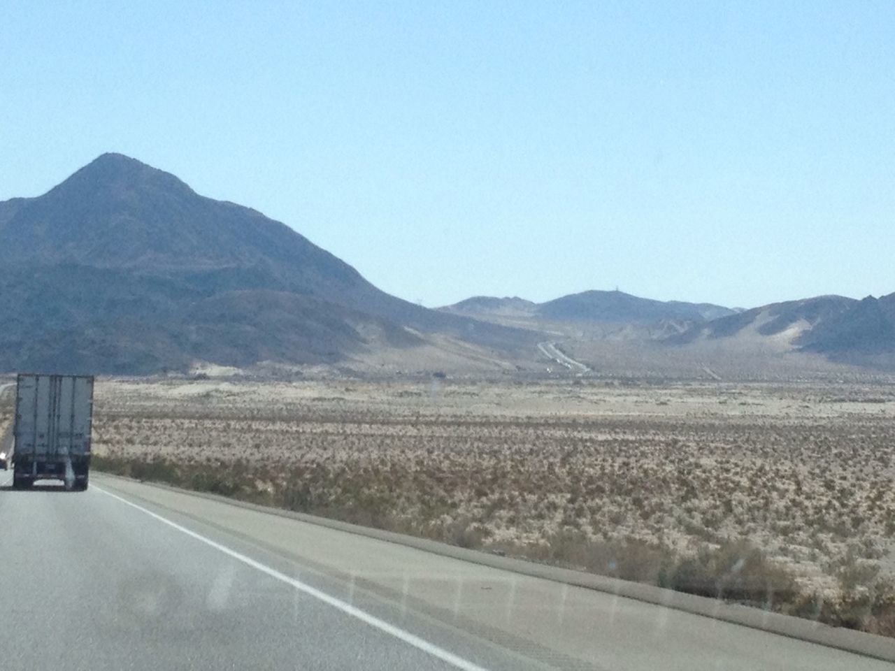 clear sky, mountain, copy space, landscape, road, tranquil scene, tranquility, mountain range, scenics, beauty in nature, field, nature, transportation, country road, blue, non-urban scene, rural scene, remote, sky, day