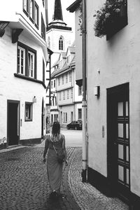 Woman walking in alley amidst buildings