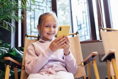 Young woman using mobile phone while sitting on sofa at home