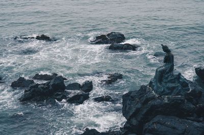 High angle view of statue on rock by sea