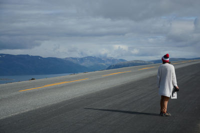 Rear view of man standing on road against sky