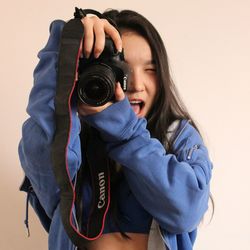 Close-up of woman holding camera over white background