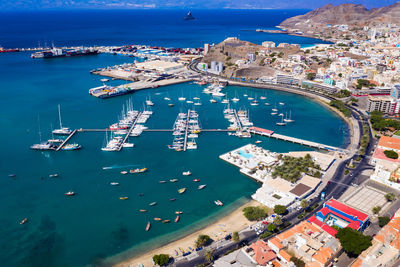 High angle view of cityscape by sea against blue sky