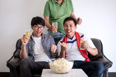 Fans enjoying beer while watching sports on tv at home