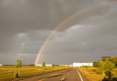 Rainbow over road against sky