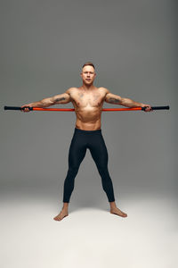 Full length of young woman exercising against white background