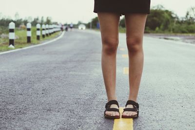 Low section of woman standing on road