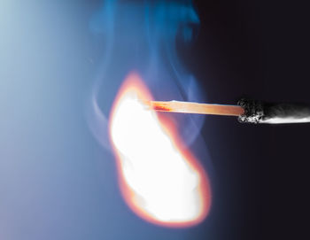 Close-up of burning matchstick over black background