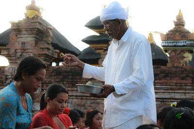 People standing outside temple against building