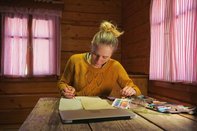 Young woman sitting on table at home