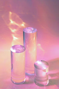 Three clear glass cylinder podiums on pastel pink background