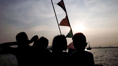 Rear view of silhouette people against sky during sunset