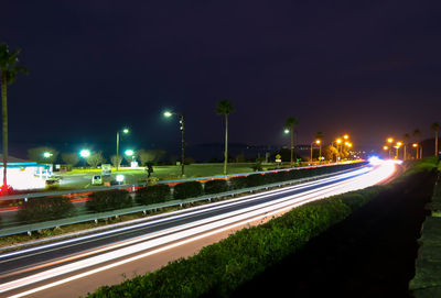 Light trails on road in city against sky at night