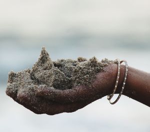 Close-up of hand holding leaf against sky