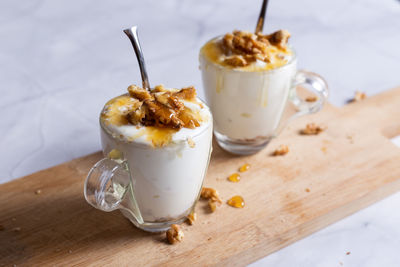 Cups of yogurt with honey and nuts on white background