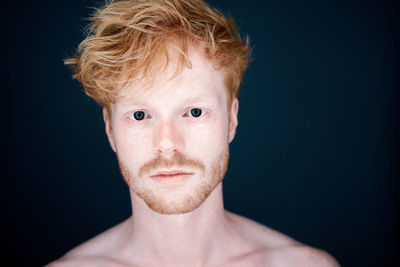 Close-up portrait of shirtless man against black background