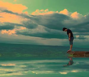 Side view of man standing in sea against sky
